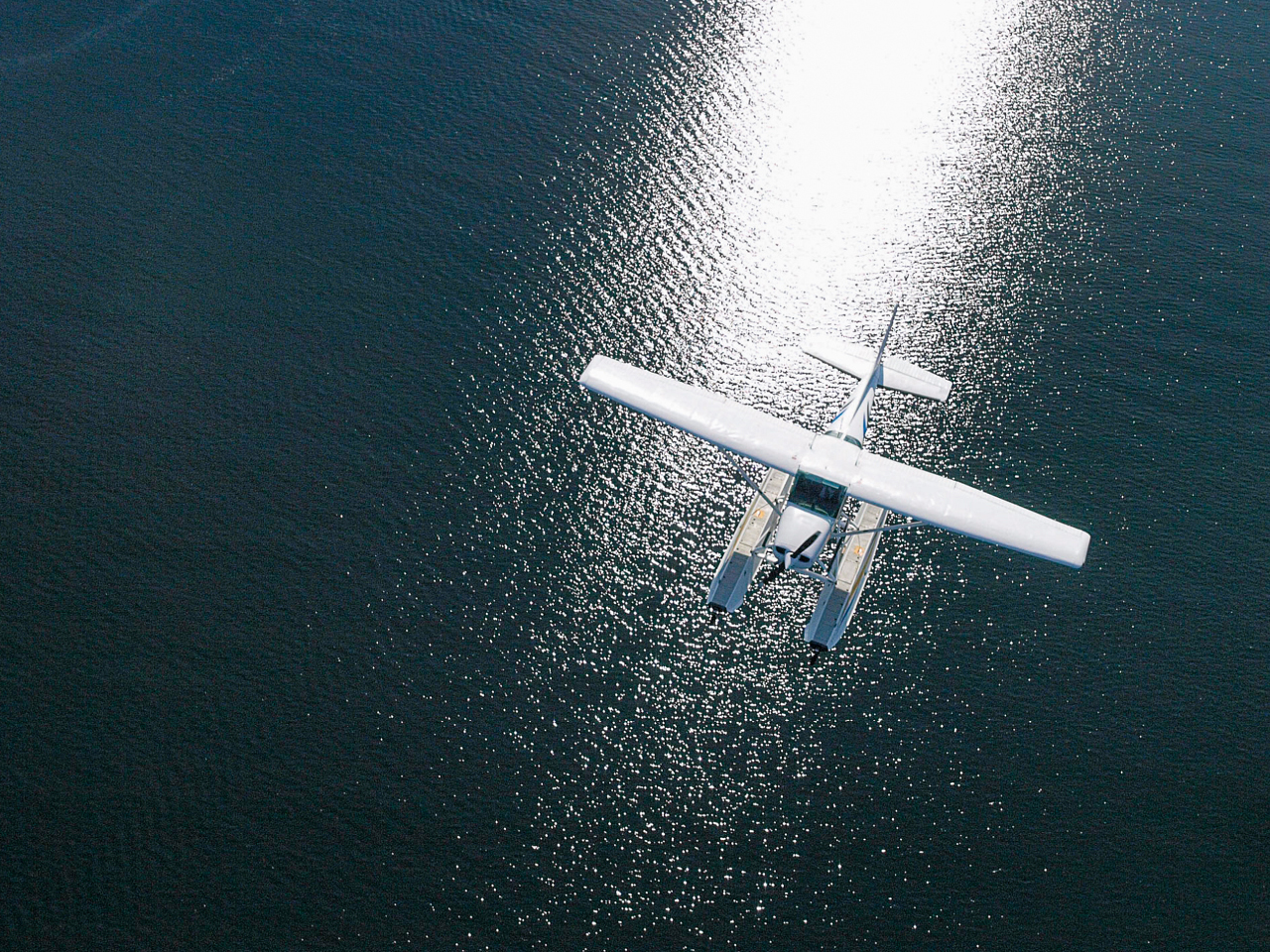 Wasserflugzeug über blauem Wasser mit der Sonne auf der Wasseroberfläche